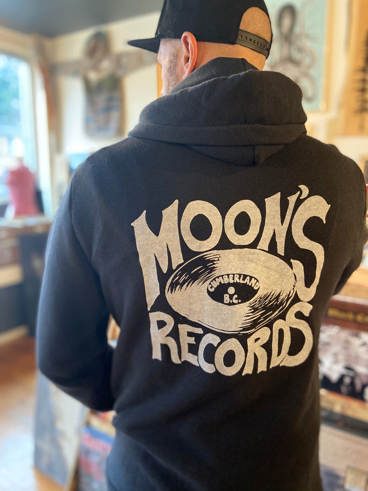 Cozy black hoodie featuring the Moon's Records logo—a vinyl record with a crescent moon design. Perfect for music lovers and slow-living enthusiasts, representing the Vancouver Island record store known for its passion for vinyl, screen-printed designs, and a laid-back coastal vibe.